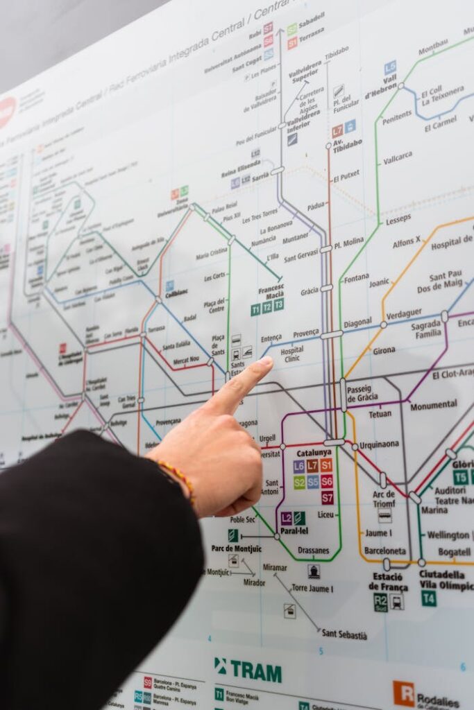 Unrecognizable person near information board pointing at map with colorful metro lines while choosing route for rise on street in city